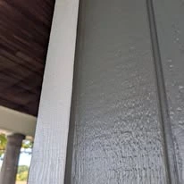 Close view of grey exterior siding, porch, and white trim