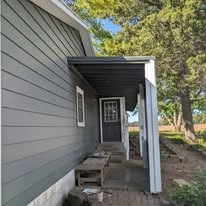 Close view of grey exterior siding, porch, and white trim